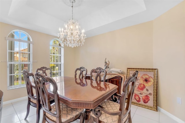 tiled dining room featuring a chandelier, a tray ceiling, and plenty of natural light