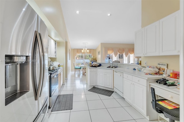 kitchen featuring appliances with stainless steel finishes, white cabinets, decorative light fixtures, and kitchen peninsula