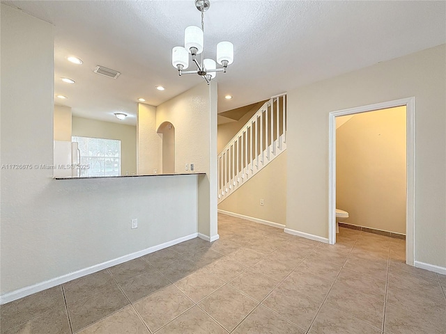 tiled empty room featuring a notable chandelier