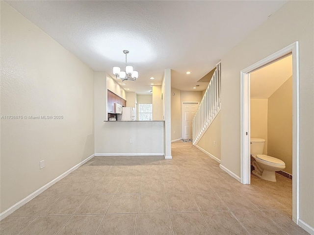 tiled empty room with a textured ceiling and a notable chandelier