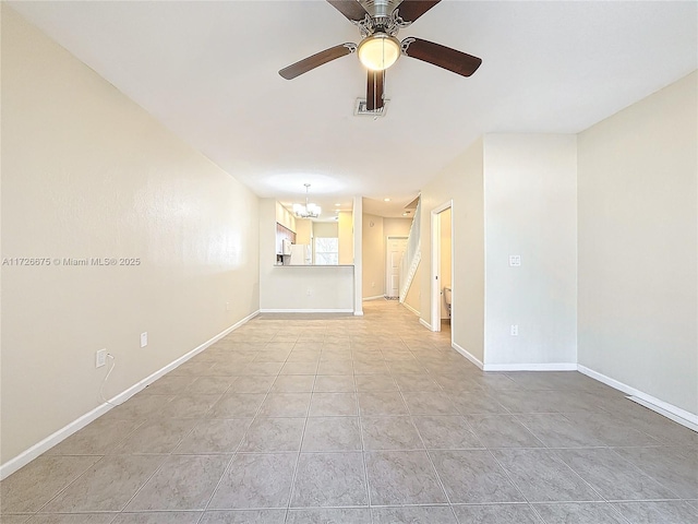 tiled empty room with ceiling fan with notable chandelier