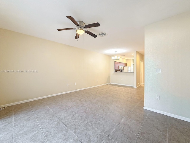 tiled empty room featuring ceiling fan with notable chandelier