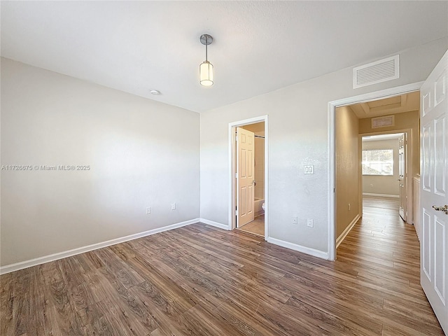 unfurnished bedroom with hardwood / wood-style flooring and connected bathroom