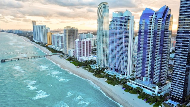 aerial view at dusk featuring a beach view and a water view