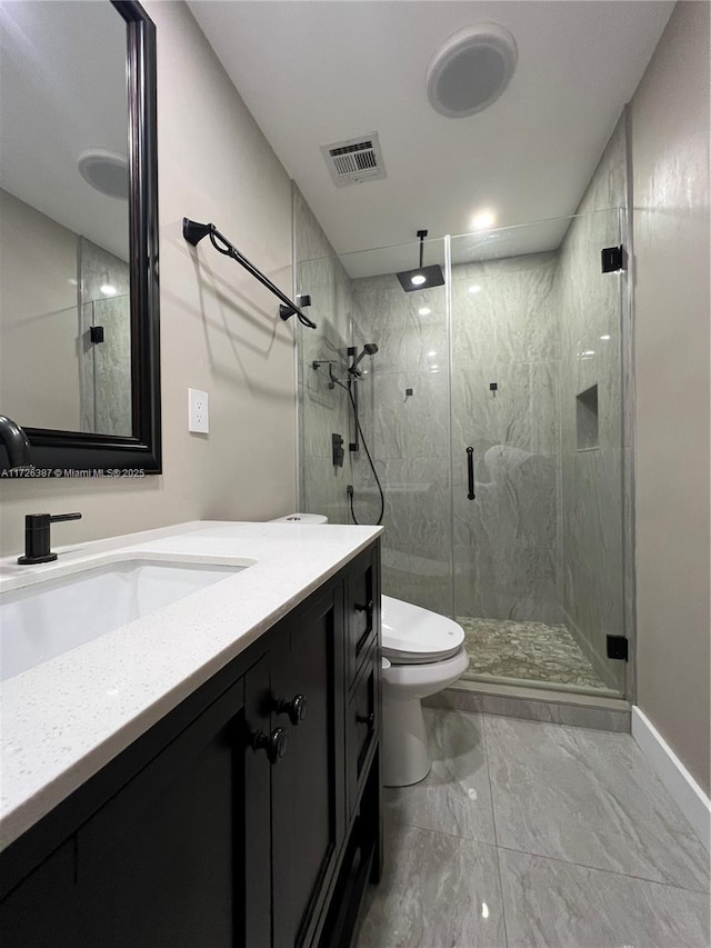 bathroom with toilet, vanity, and a shower with shower door