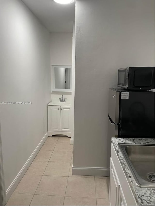 kitchen featuring sink, white cabinetry, stainless steel refrigerator, and light tile patterned floors