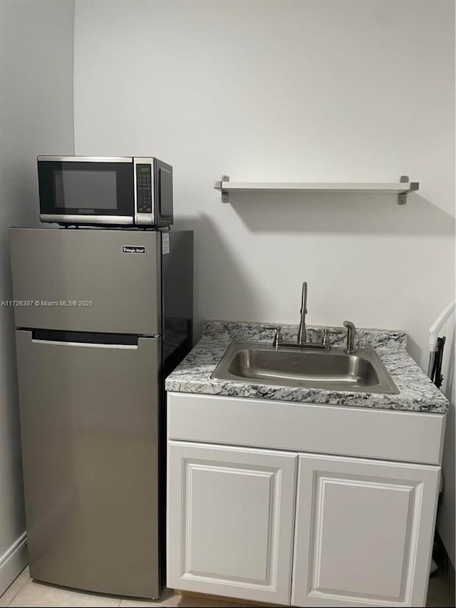 kitchen featuring sink, white cabinetry, light tile patterned floors, and appliances with stainless steel finishes