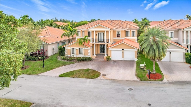 mediterranean / spanish home featuring a balcony, a garage, a residential view, driveway, and a tiled roof