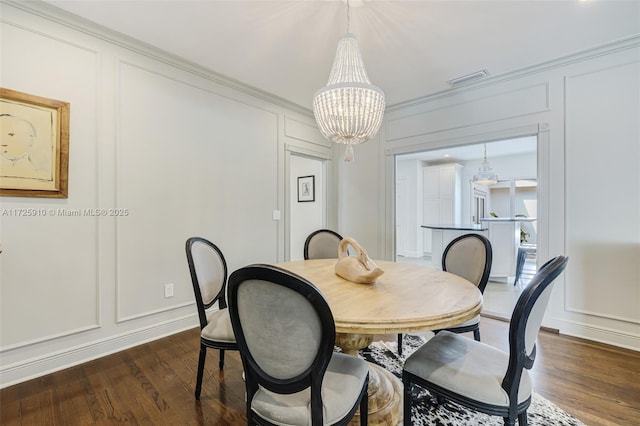 dining room with dark wood-type flooring, ornamental molding, and a chandelier