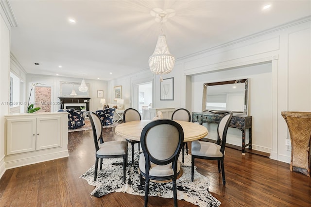 dining area featuring dark wood-type flooring, ornamental molding, and a notable chandelier