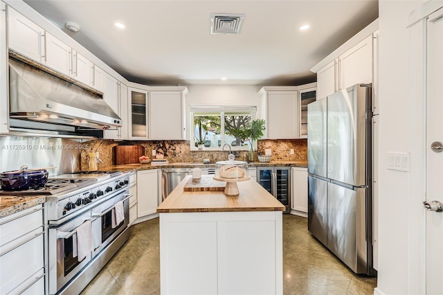 kitchen featuring white cabinetry, butcher block counters, stainless steel appliances, and a kitchen island