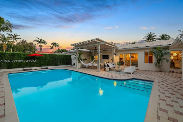 pool at dusk featuring a patio