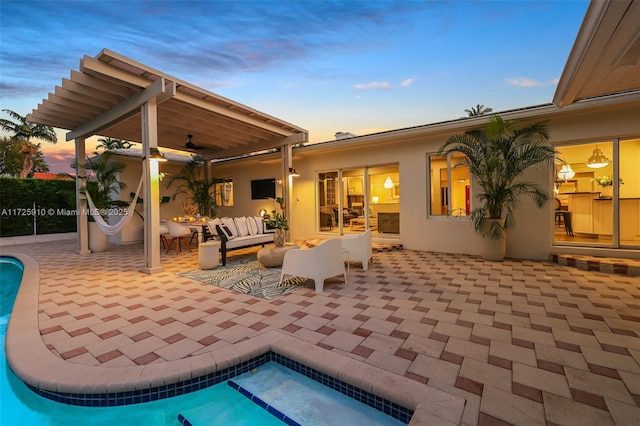 patio terrace at dusk with ceiling fan, outdoor lounge area, and a jacuzzi