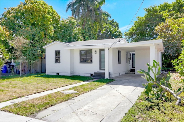 view of front facade featuring stucco siding, driveway, a front lawn, fence, and a carport