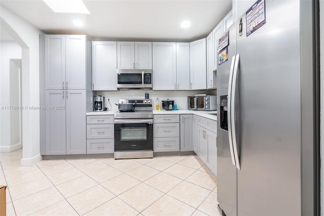 kitchen with stainless steel appliances, light tile patterned floors, and gray cabinets