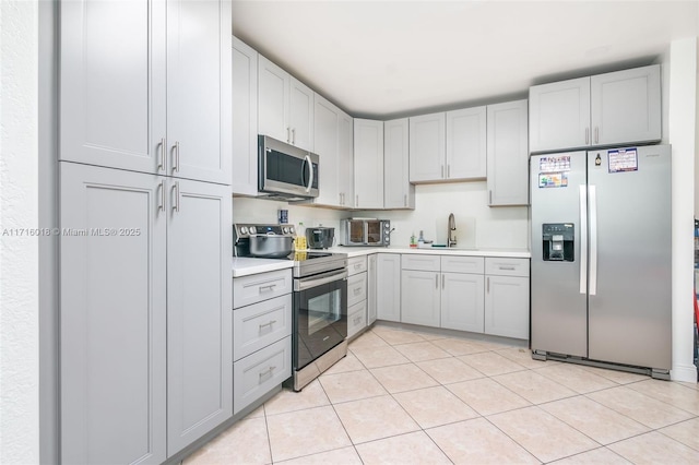 kitchen with stainless steel appliances, light tile patterned flooring, and sink