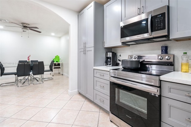 kitchen featuring ceiling fan, appliances with stainless steel finishes, light tile patterned flooring, and gray cabinets