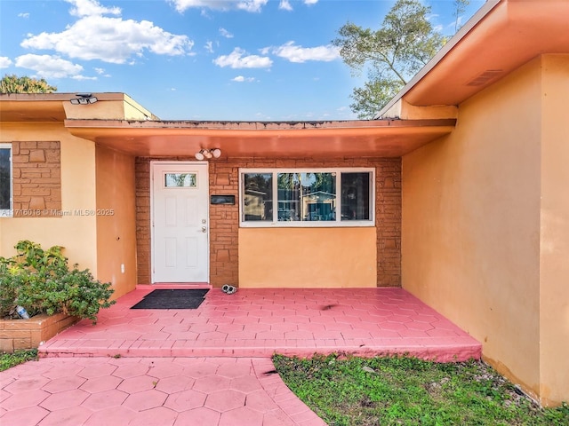 view of exterior entry with a patio