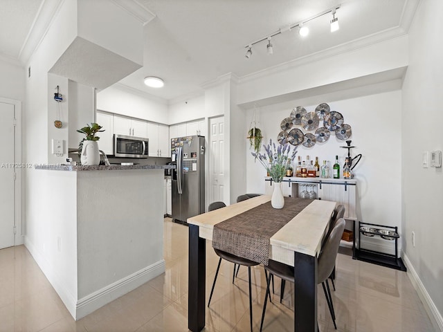 dining space with crown molding, track lighting, and light tile patterned floors