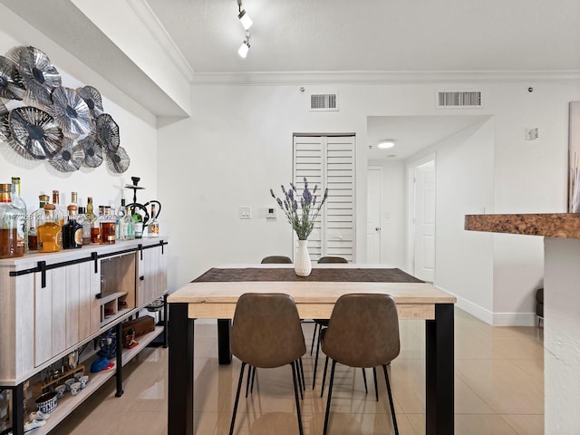 tiled dining area featuring bar, a textured ceiling, rail lighting, and crown molding