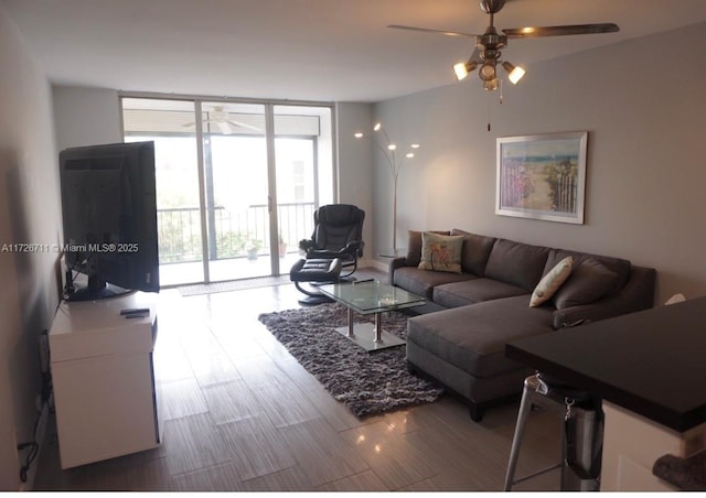 living room with ceiling fan, expansive windows, and wood-type flooring