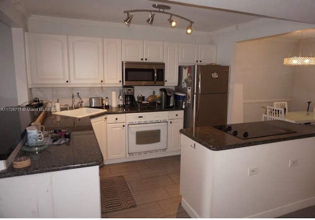 kitchen with stainless steel appliances, sink, white cabinets, dark stone countertops, and hanging light fixtures