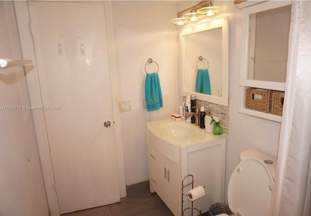 bathroom featuring toilet, vanity, and decorative backsplash