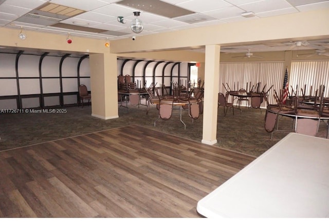 interior space featuring a drop ceiling, ceiling fan, and wood-type flooring