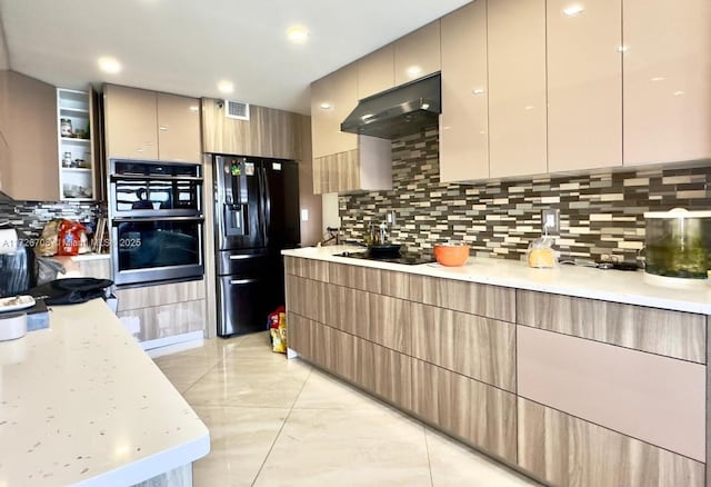 kitchen featuring black appliances, light stone counters, decorative backsplash, and light brown cabinets