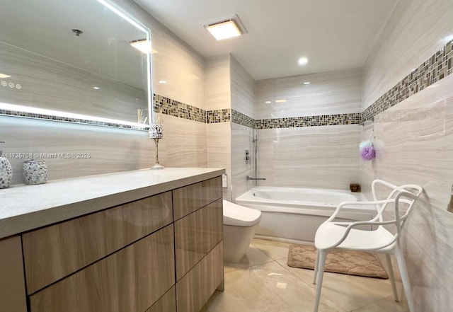 full bathroom with tile patterned flooring, toilet, vanity, tile walls, and shower / tub combination