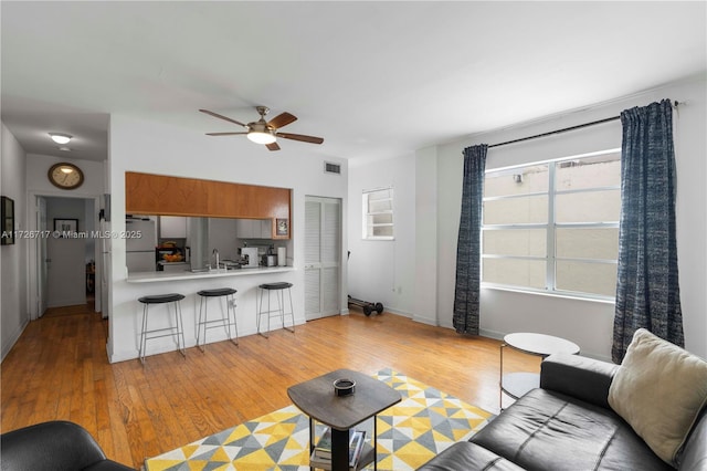 living room with light hardwood / wood-style floors and ceiling fan