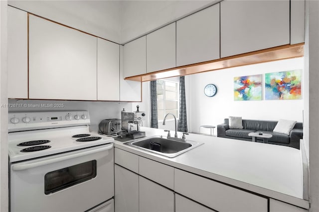 kitchen with sink, electric stove, and white cabinetry