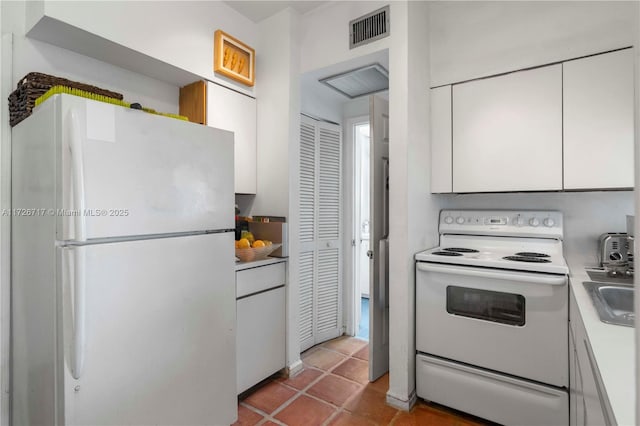 kitchen featuring white appliances, white cabinetry, and light tile patterned flooring