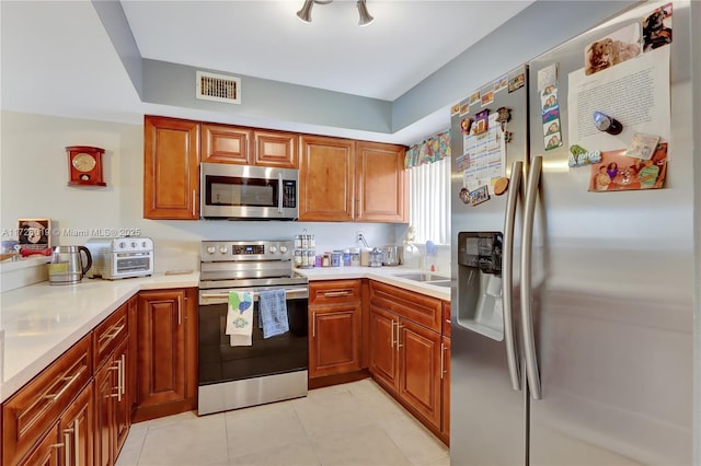 kitchen with sink, light tile patterned floors, and stainless steel appliances