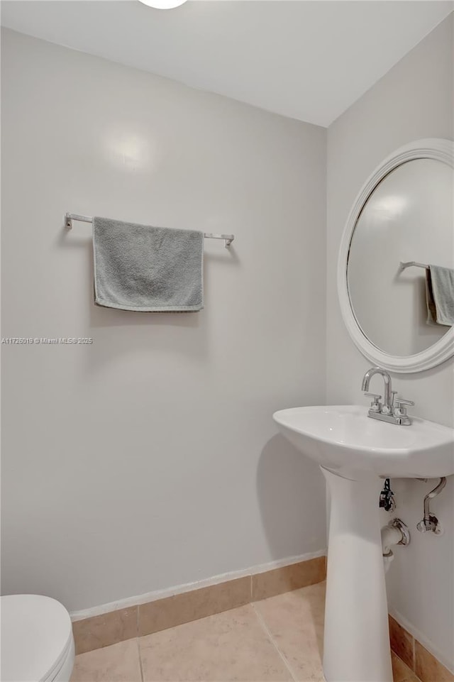 bathroom with toilet, tile patterned floors, and sink