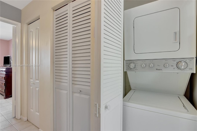 laundry area with light tile patterned floors and stacked washer / drying machine