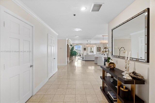 corridor featuring an inviting chandelier, crown molding, and light tile patterned floors