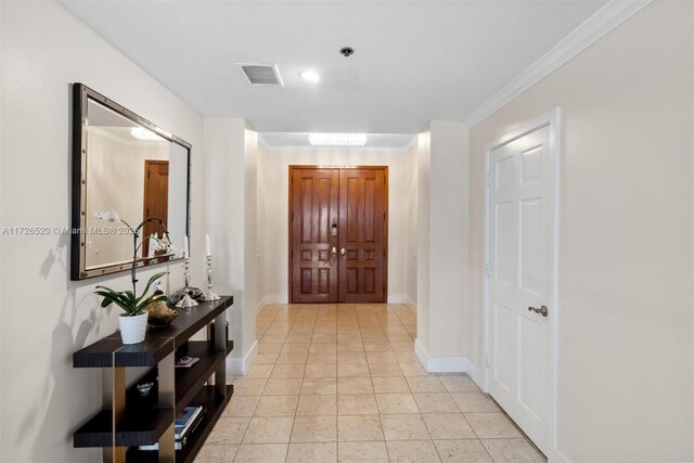 hallway featuring ornamental molding and light tile patterned floors