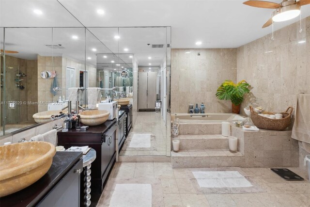 bathroom featuring tile walls, ceiling fan, independent shower and bath, and vanity