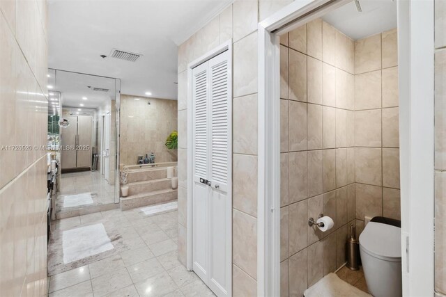 bathroom with toilet, tile walls, and plus walk in shower