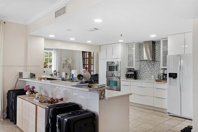 kitchen with white cabinets, wall chimney range hood, sink, and white refrigerator with ice dispenser