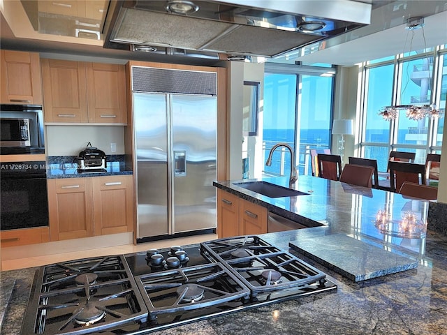 kitchen featuring sink, a water view, exhaust hood, pendant lighting, and black appliances