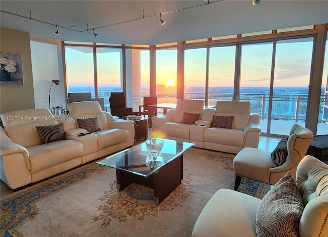 living room with a water view, rail lighting, and floor to ceiling windows