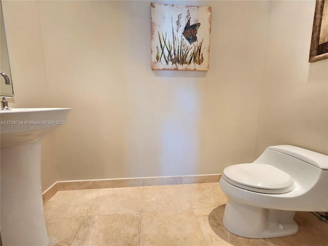 bathroom with baseboards, tile patterned floors, and toilet