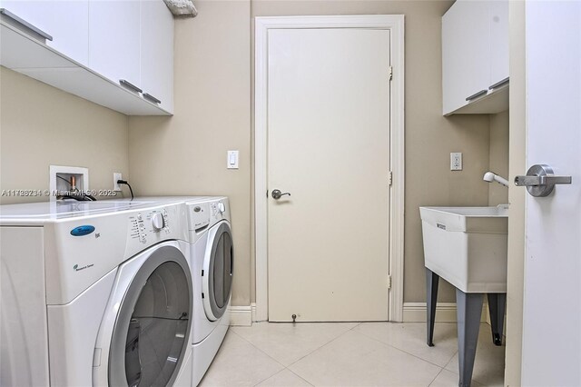 washroom with cabinets, washing machine and clothes dryer, and light tile patterned floors