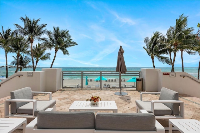 view of patio with a water view, a balcony, and a view of the beach