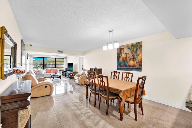 dining space with light tile patterned flooring, a chandelier, and a textured ceiling