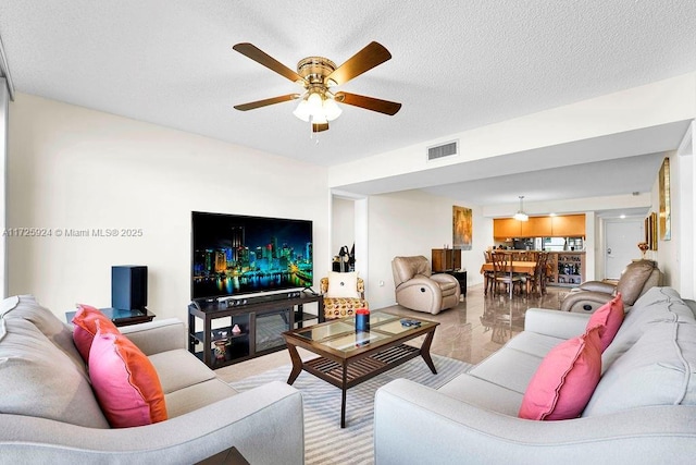 living room with ceiling fan and a textured ceiling