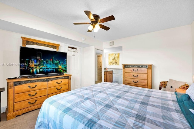 bedroom with connected bathroom, a textured ceiling, ceiling fan, and light tile patterned floors