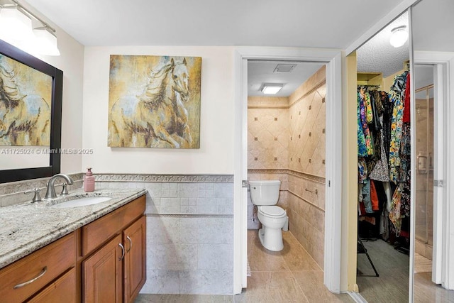 bathroom with vanity, tile walls, and toilet